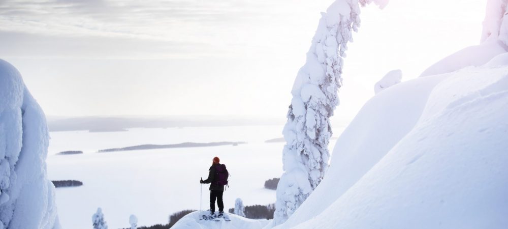 Nainen seisoo lumikengät jalassa Kolin huipulla