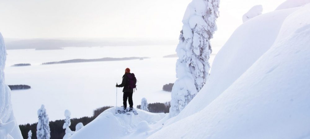 Nainen seisoo lumikengät jalassa Kolin huipulla