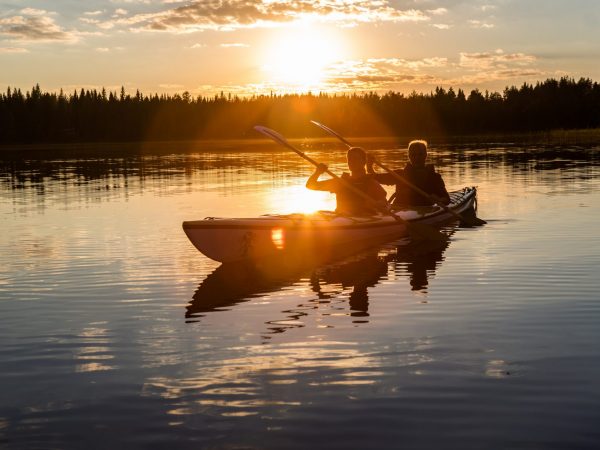 Melojat tyynellä järvellä auringonlaskun aikaan